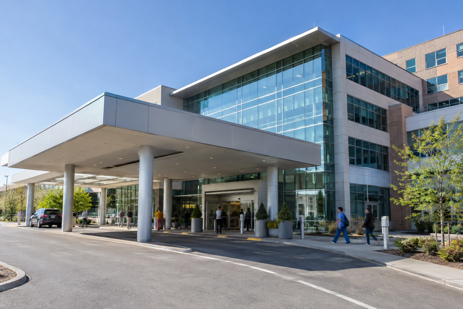 A modern hospital exterior and entrance area on a bright day.